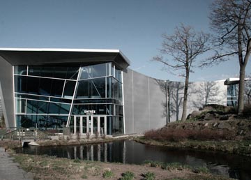 L'entrée vitrée de l'Aquarium de Québec, ses murs de béton, le bassin et les arbres