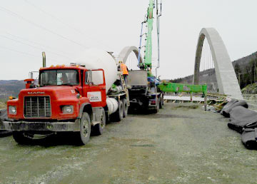 La coulée du pont en arche : une bétonnière rouge et le bras de la pompe devant l'arche en chantier
