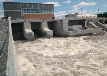 Le déversoir Sartigan en crue, l'eau blanche qui dévale les vannes de béton