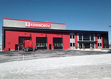 Le garage St-George : la façade rouge du concessionnaire Kenworth et ses portes de service numérotées