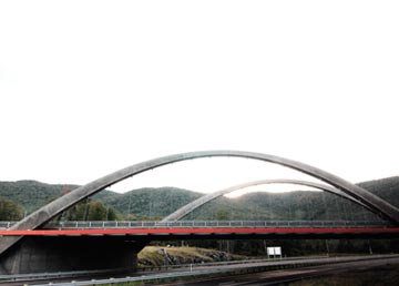 Le pont en arche blanc qui franchit la vallée, la route en contrebas et les montagnes derrière