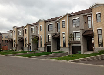 Une rangée de maisons de ville neuves à Québec, trottoirs et pelouses