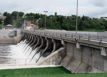 Le barrage Sartigan : la longue crête de béton, ses vannes et la route qui passe dessus